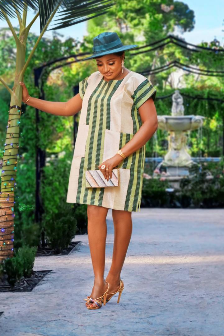 Cream and green striped day dress styled with a green fedora, clutch and gold heels