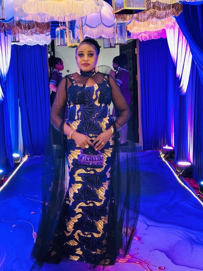 Navy and gold Ankara column gown with sheer black tulle overlay on a lit runway