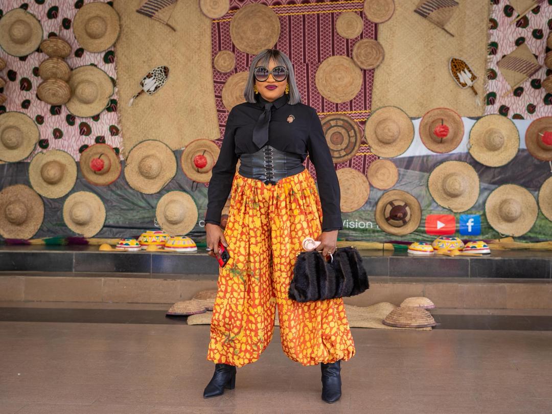 Avant-garde orange Ankara harem trousers with a black shirt and leather corset belt